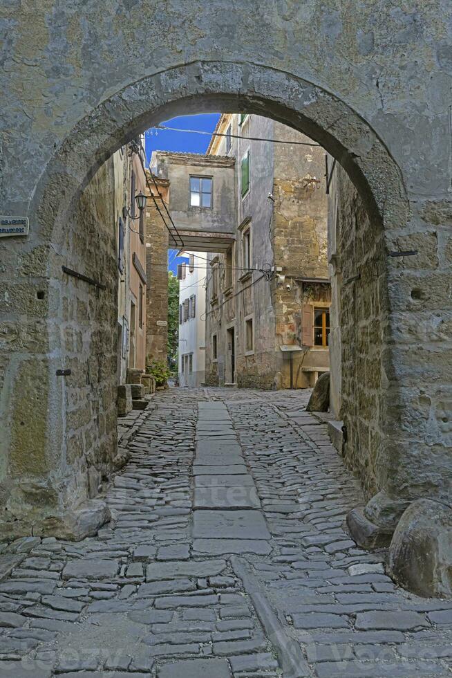 View through an arched gateway along a cobbled street into an ancient village without people 34050511 Stock Photo at Vecteezy