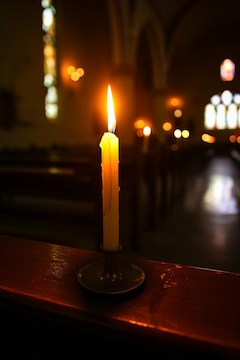 A single candle burning in a darkened church | Premium AI-generated image